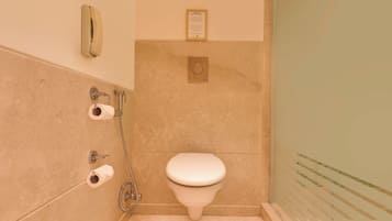 Un baño con inodoro, bidé y dispensador de toallas de papel.
