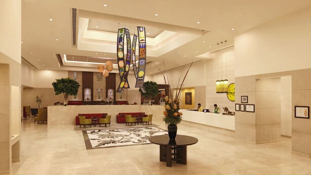Eine geräumige Lobby mit einer Rezeption, einer Sitzecke und einer dekorativen Vase mit Blumen.