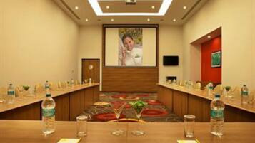 A conference room with a long table, water bottles, glasses, and a projector screen.