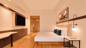 Ein Hotelzimmer mit Bett, Nachttisch und einem Wandfernseher.