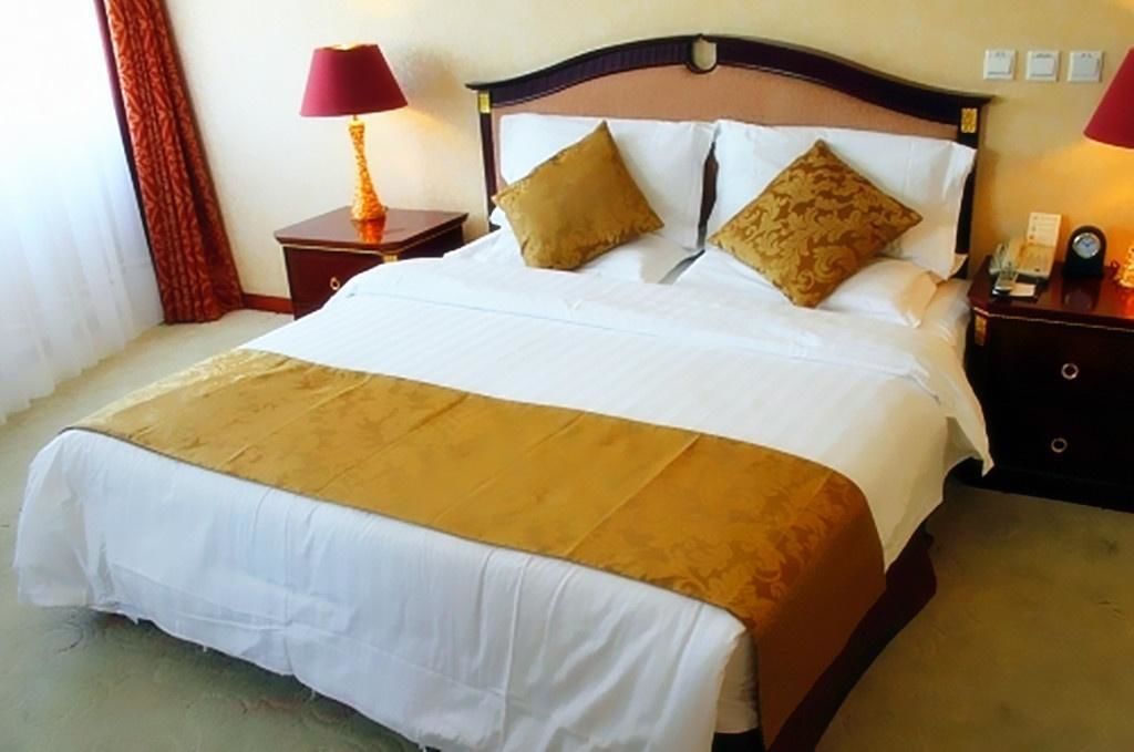 A hotel room with a large bed, two bedside tables, a lamp, and a nightstand.