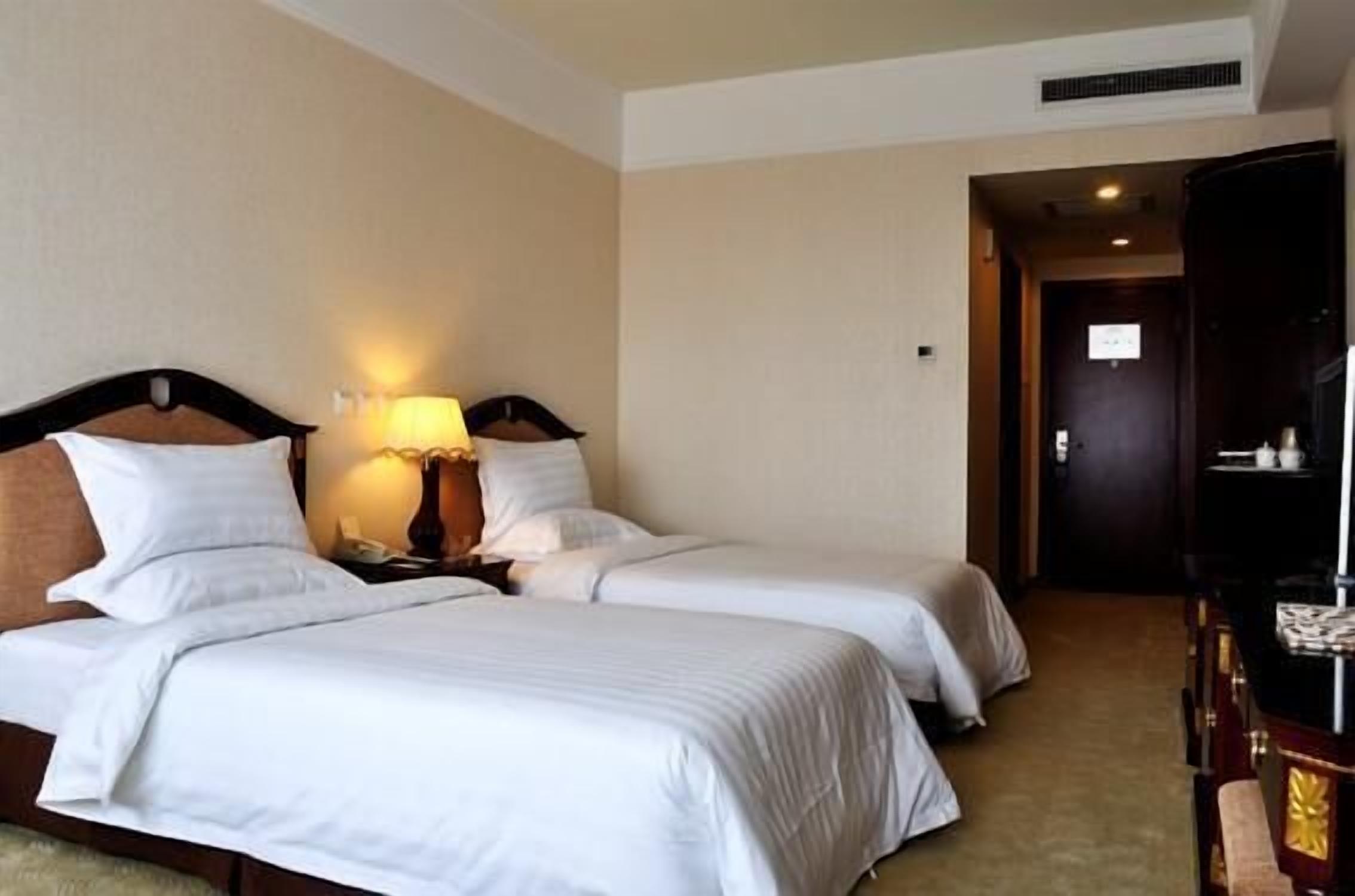 A hotel room with two beds, a desk, and a piano.