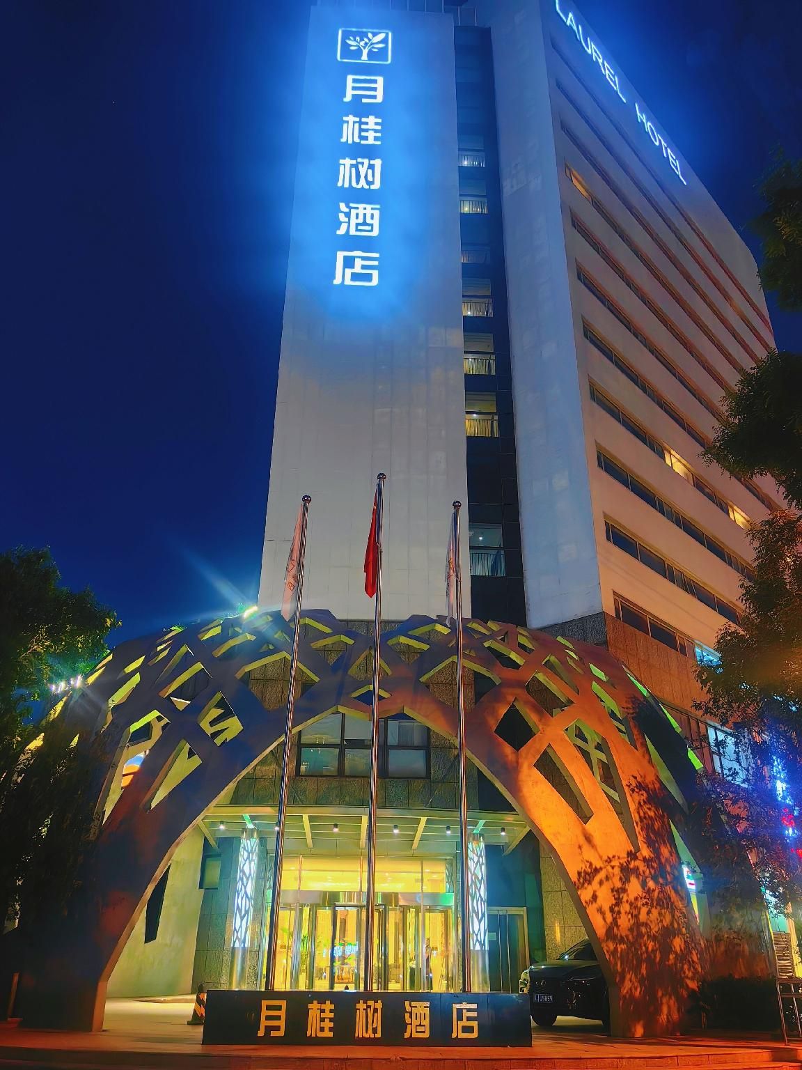 A hotel with a modern facade, featuring a prominent sign with Chinese characters and a logo.