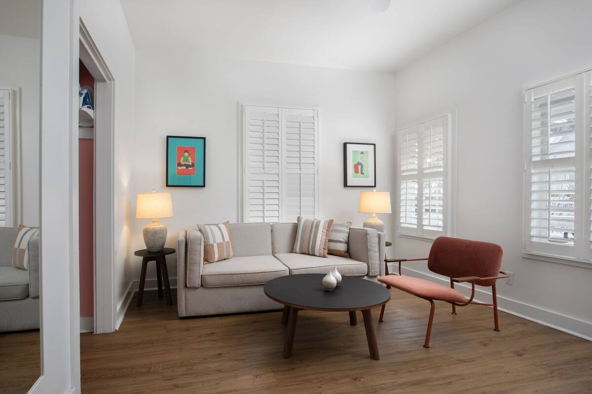 A living room with a sofa, a round table, a chair, a lamp, and a picture frame on the wall.