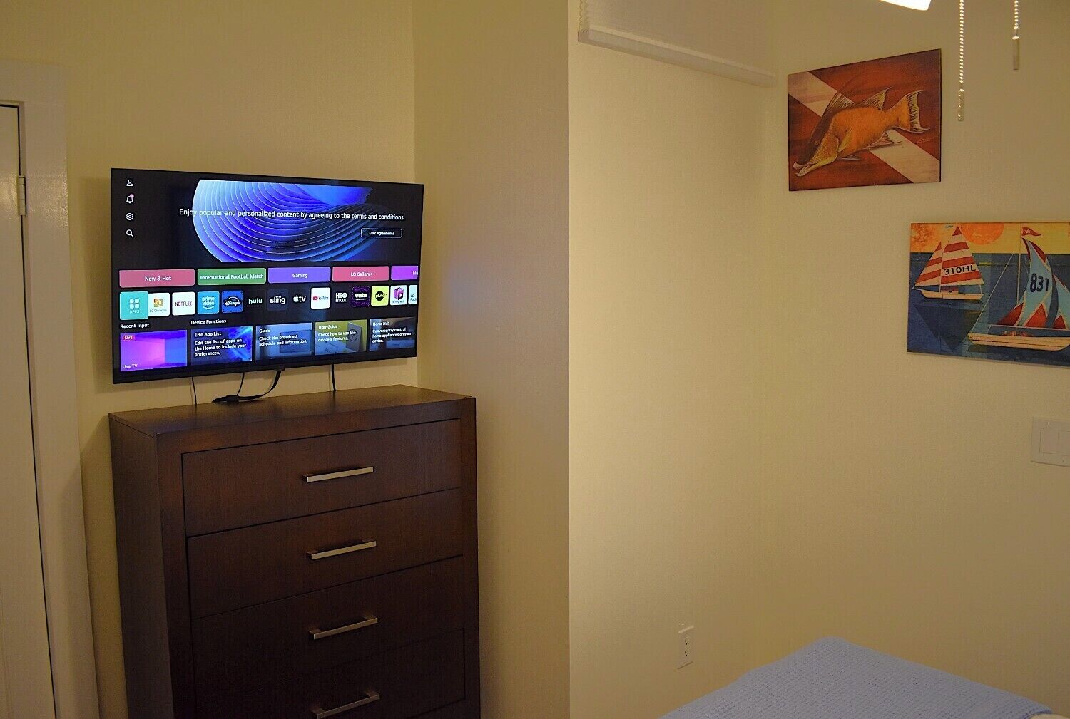 A flat-screen TV mounted on a wooden cabinet with a wall art piece above it.