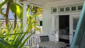 A covered outdoor area with a table and chairs, surrounded by white railings and green foliage. - Paradise Inn Key West - Adults Only (Key West)
