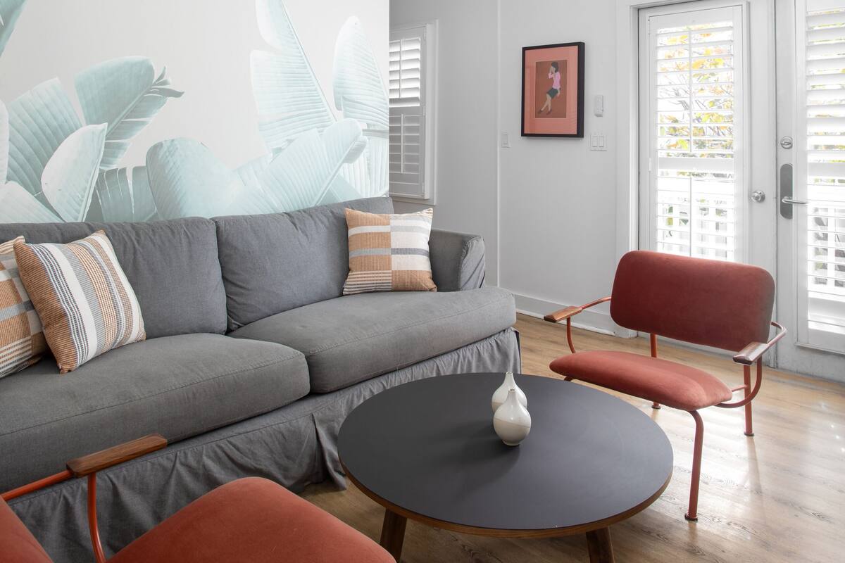 A modern living room with a gray sectional sofa, a round coffee table, and a red chair.