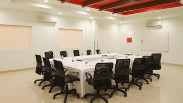 A conference room with a long table, black chairs, white tablecloths, and water bottles.