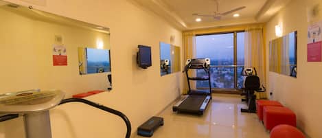 A gym with a treadmill, exercise bike, and red exercise balls.