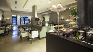 A modern hotel lobby with a bar area, seating arrangements, and a buffet with various food items. - Grand Hotel Villa Itria (Viagrande)
