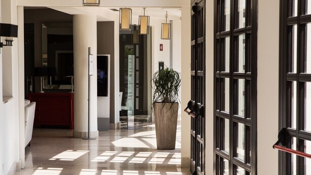 A spacious hallway with a polished floor, large windows, and a potted plant. - Grand Hotel Villa Itria (Viagrande)