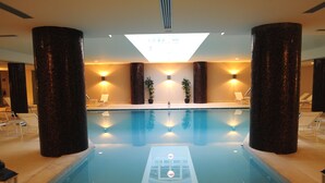 A swimming pool with a sunken seating area, surrounded by large pillars, and two potted plants. - Grand Hotel Villa Itria (Viagrande)
