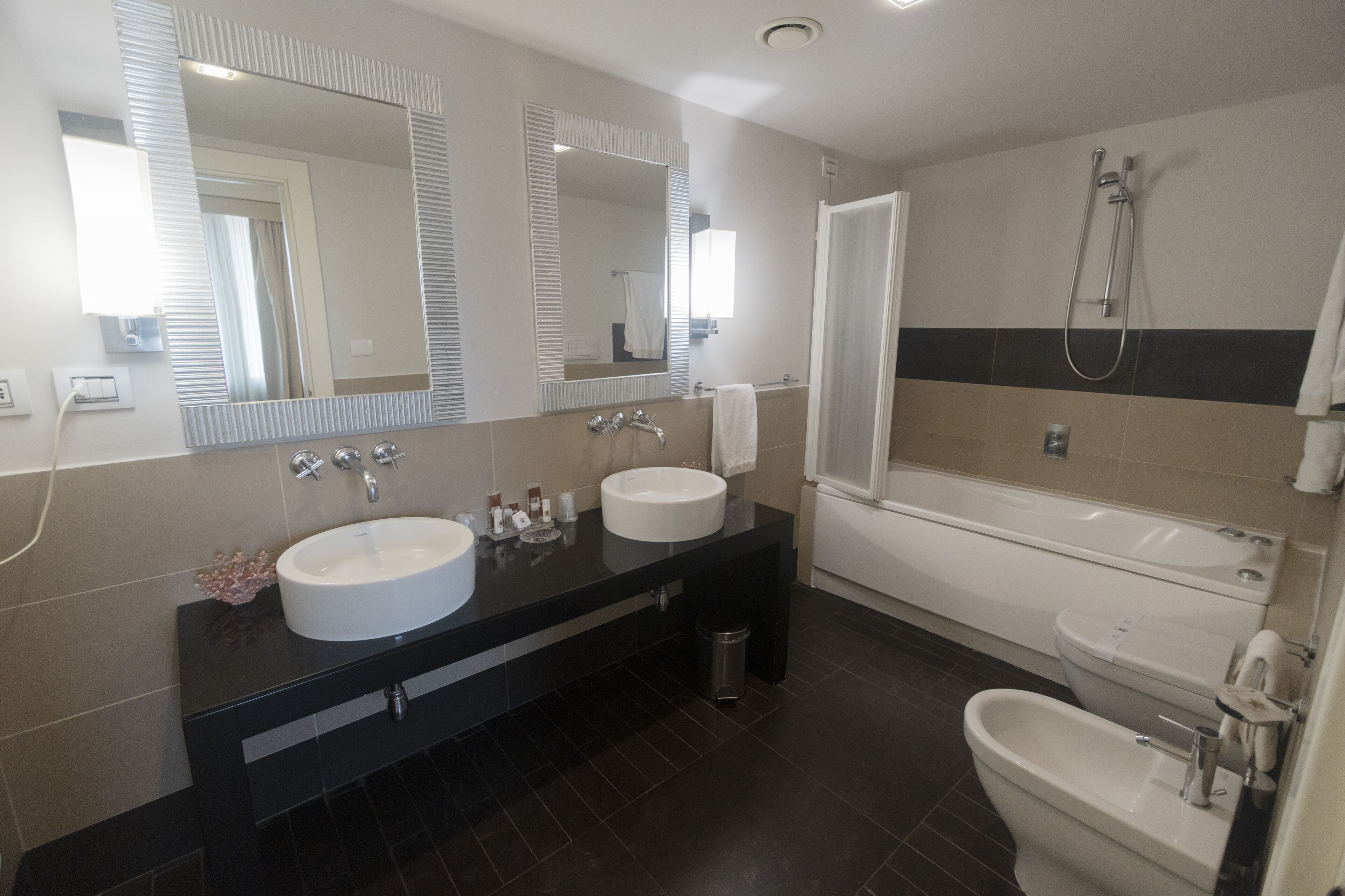 Uma casa de banho moderna com duas pias, uma banheira e um chuveiro.