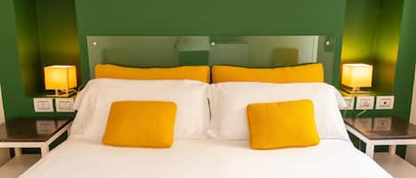 Une chambre d’hôtel avec un grand lit, des murs verts et deux lampes de chevet.