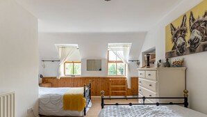 A bedroom with two beds, a dresser, a mirror, and a painting. - Priest Bridge Cottage (Newcastle)