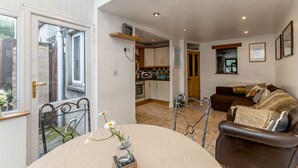 A spacious living area with a dining table, a sofa, and a kitchen in the background. - Priest Bridge Cottage (Newcastle)