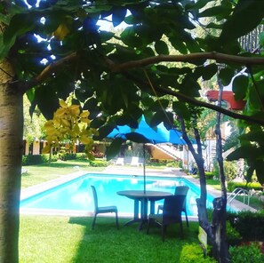 Una piscina al aire libre, sombrillas, sillones reclinables de piscina