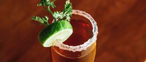 A cocktail glass with a salted rim and a lime garnish on a wooden surface.