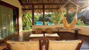 A wooden deck with a hammock, two wicker chairs, and a table. - Loharano Lodge (Nosy Be)