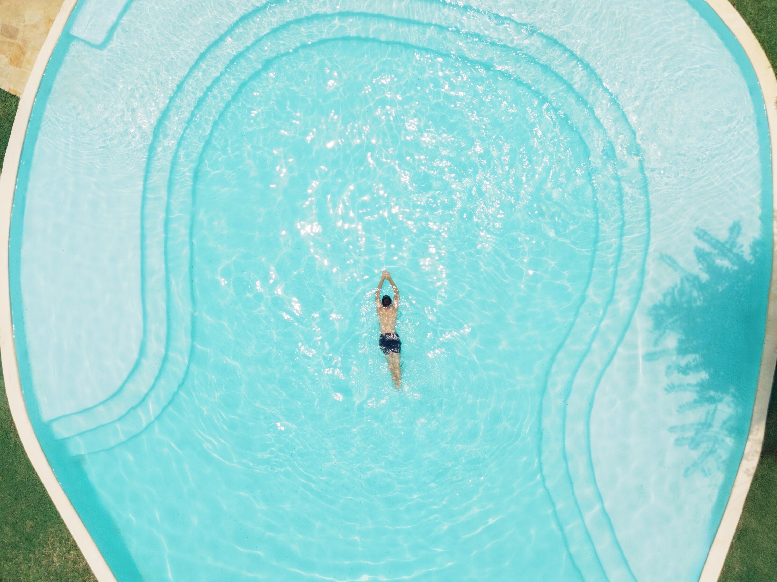 An aerial view of a swimming pool with a person swimming.