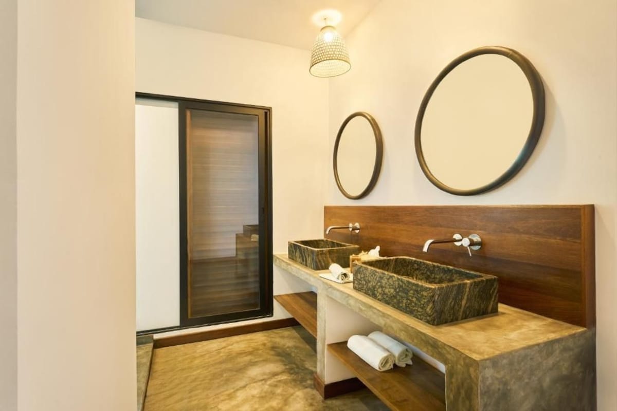 A modern bathroom with two sinks, a wooden vanity, and a large mirror.