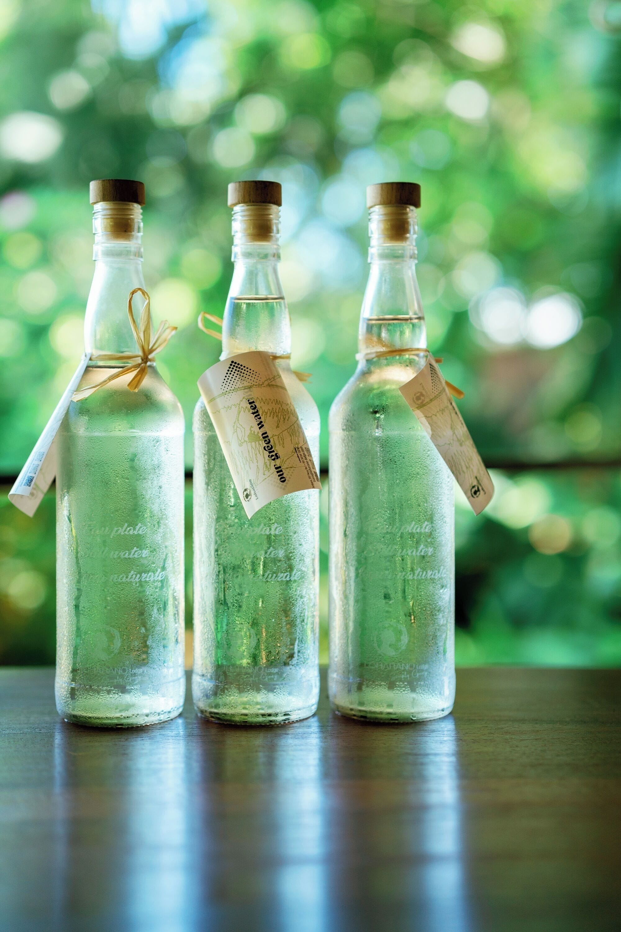 Three glass bottles with tags on a wooden surface.