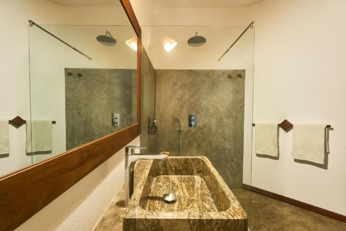 A bathroom with a large mirror, a freestanding bathtub, a shower area, and towels hanging on the wall.