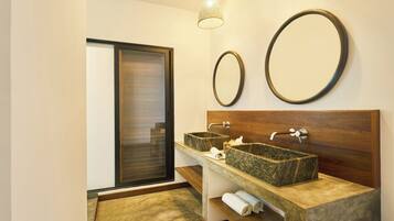 A modern bathroom with two granite sinks, a wooden vanity, a large mirror, and a glass door leading to a balcony.