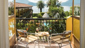 Un balcon avec une table et des chaises, offrant une vue panoramique sur un lac et des montagnes.