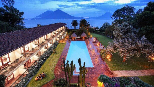 Un complexe hôtelier doté d’une piscine, d’un patio couvert et offrant une vue sur l’océan et les montagnes.