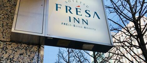 Señalización de 'Sotetsu Fresna Inn', con un cielo despejado y árboles sin hojas al fondo.