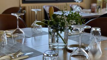 A dining table set with clear glassware, a vase with flowers, and a candle holder.