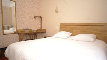 Una habitación de hotel con una cama grande, un cabecero de madera, una mesita de noche, un espejo y una lámpara de pared.