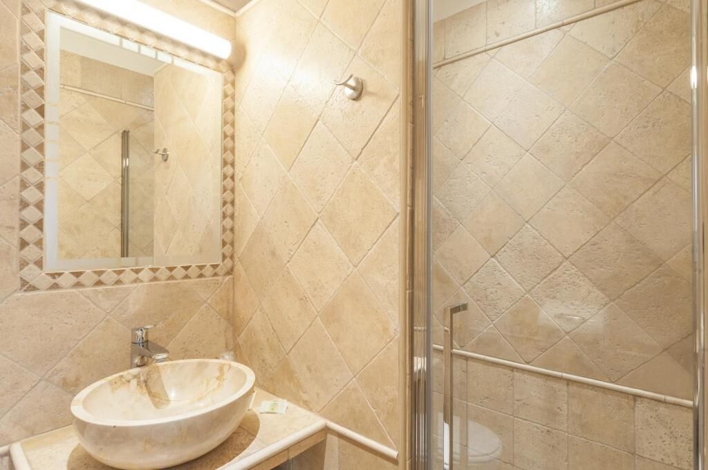 A bathroom with a large mirror, a sink, and a shower area.