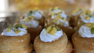 A tray of cream puffs topped with whipped cream and fruit.