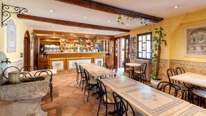 Un restaurante con una mesa común larga, mesas individuales y una zona de bar.