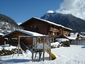 Un hotel in stile chalet di legno con una seggiovia e un paesaggio montano innevato.