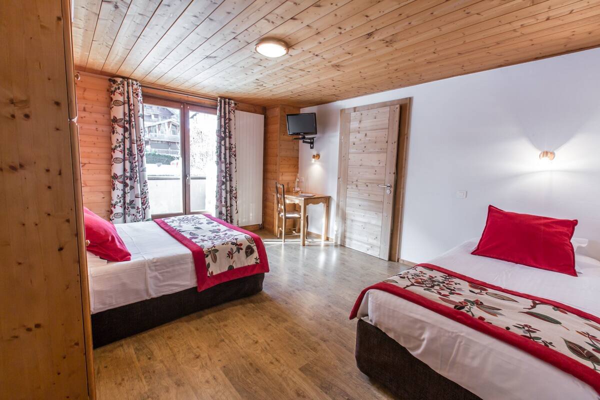 Ein Zimmer mit Holzwänden, zwei Betten, einem Schreibtisch und einem Fernseher.