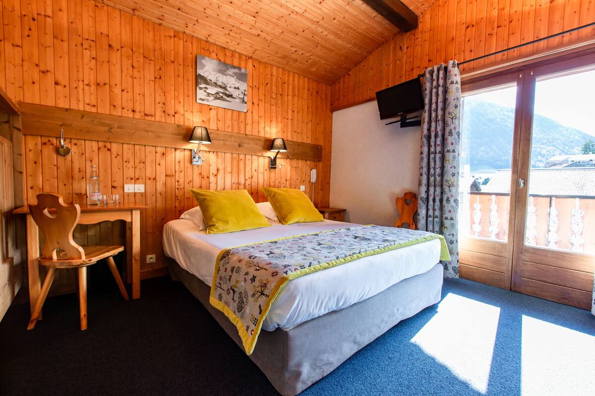 Ein Zimmer aus Holz mit einem Bett, einem Schreibtisch und einem Stuhl.