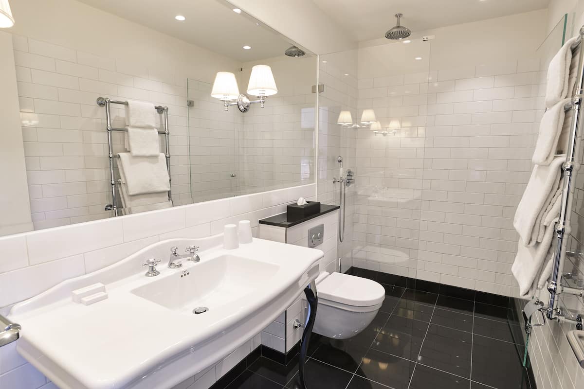 Un baño moderno con un espejo grande, un lavabo blanco y una cabina de ducha de vidrio.