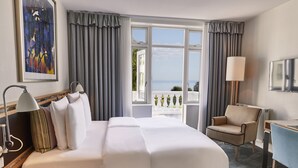 Habitación de hotel con una cama grande, un escritorio, una silla y vista al mar.