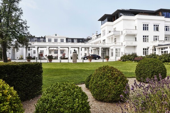 A large, white, multi-story building with a symmetrical facade, a central entrance with columns, and a well-maintained garden with hedges and lavender. - Kurhotel Skodsborg (Skodsborg)