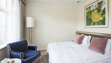 Una habitación de hotel con una cama, una silla, una lámpara y una ventana.