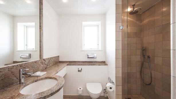 Un baño moderno con lavamanos de granito, inodoro y zona de ducha.