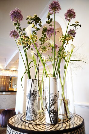 A round table with vases containing flowers and decorative branches. - Kurhotel Skodsborg (Skodsborg)