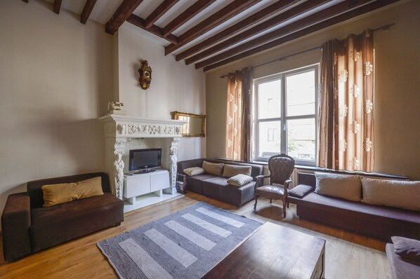 Una sala de estar con chimenea, sofás, televisor y ventana con cortinas.