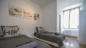 Un dormitorio con dos camas, un radiador y una ventana con cortinas.