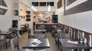 Un restaurante con varias mesas y sillas, un candelabro y un menú en una pizarra.