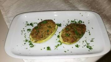 Zwei panierten Patties auf einem weißen Teller, garniert mit Petersilie.