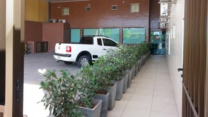 A white pickup truck parked in a covered parking area with a row of potted plants in the foreground. - Hotel Veraneio (Recife)